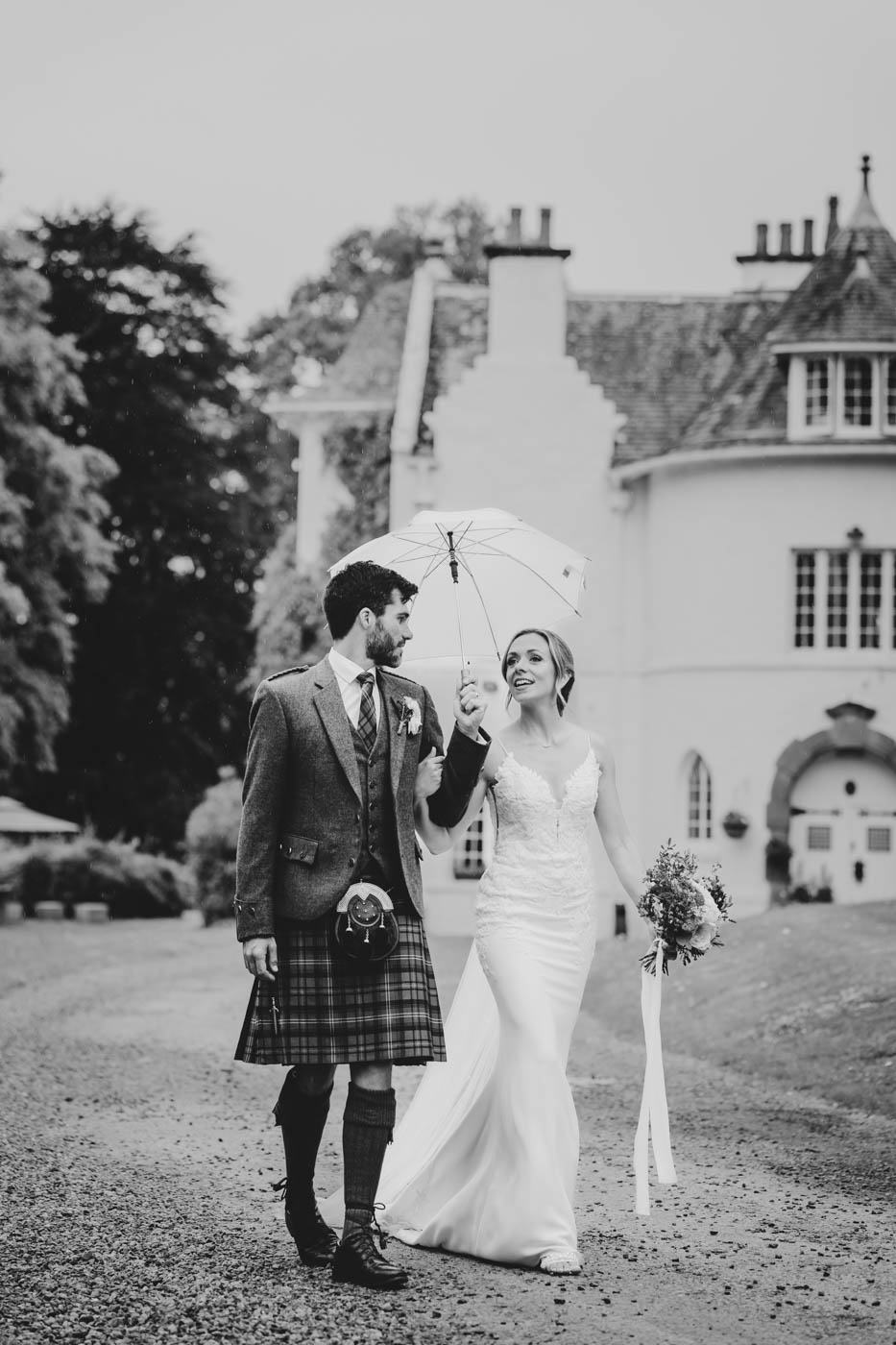 black and white photo of couple with Scottish Castle in background